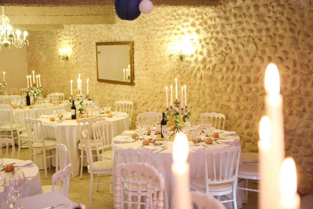 Tables dressées a l'occasion d'un mariage dans une grande pièce aux murs en pierre