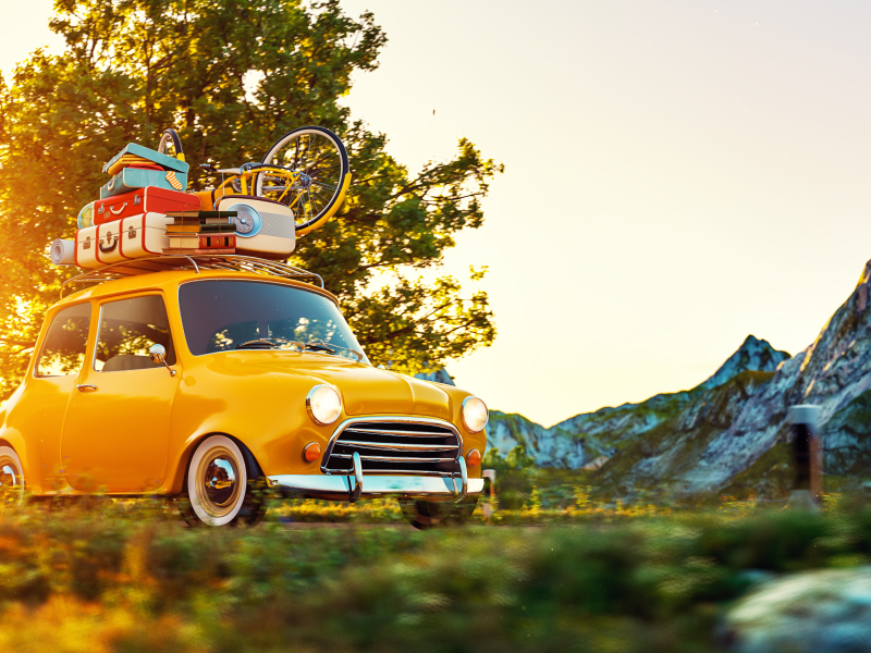 Petite voiture jaune en montagne avec bagages arrimés sur le toit