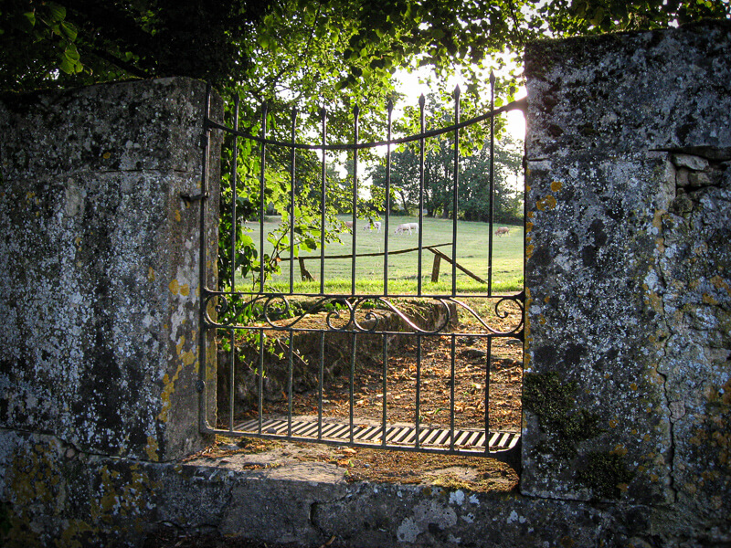 Un portail dans le mur d'enceinte du domaine de Garraube donnant sur un champs voisin