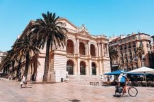 People cross a public square in front of a neoclassical building in Toulon.