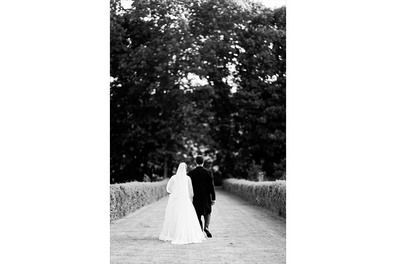 Les deux mariés pris de dos sur un pont en noir et blanc